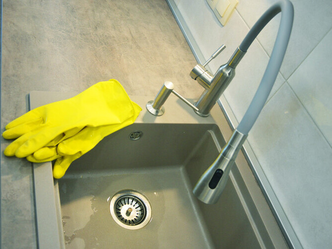 Yellow household cleaning gloves lie on the utility sink.